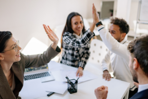 Happy employees high five over their employee benefits program